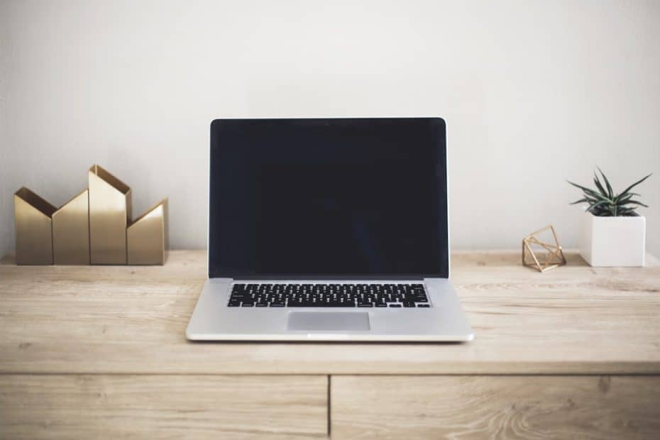 Modern laptop on a wooden desk with decorative items, representing bookkeeping services in New Braun.